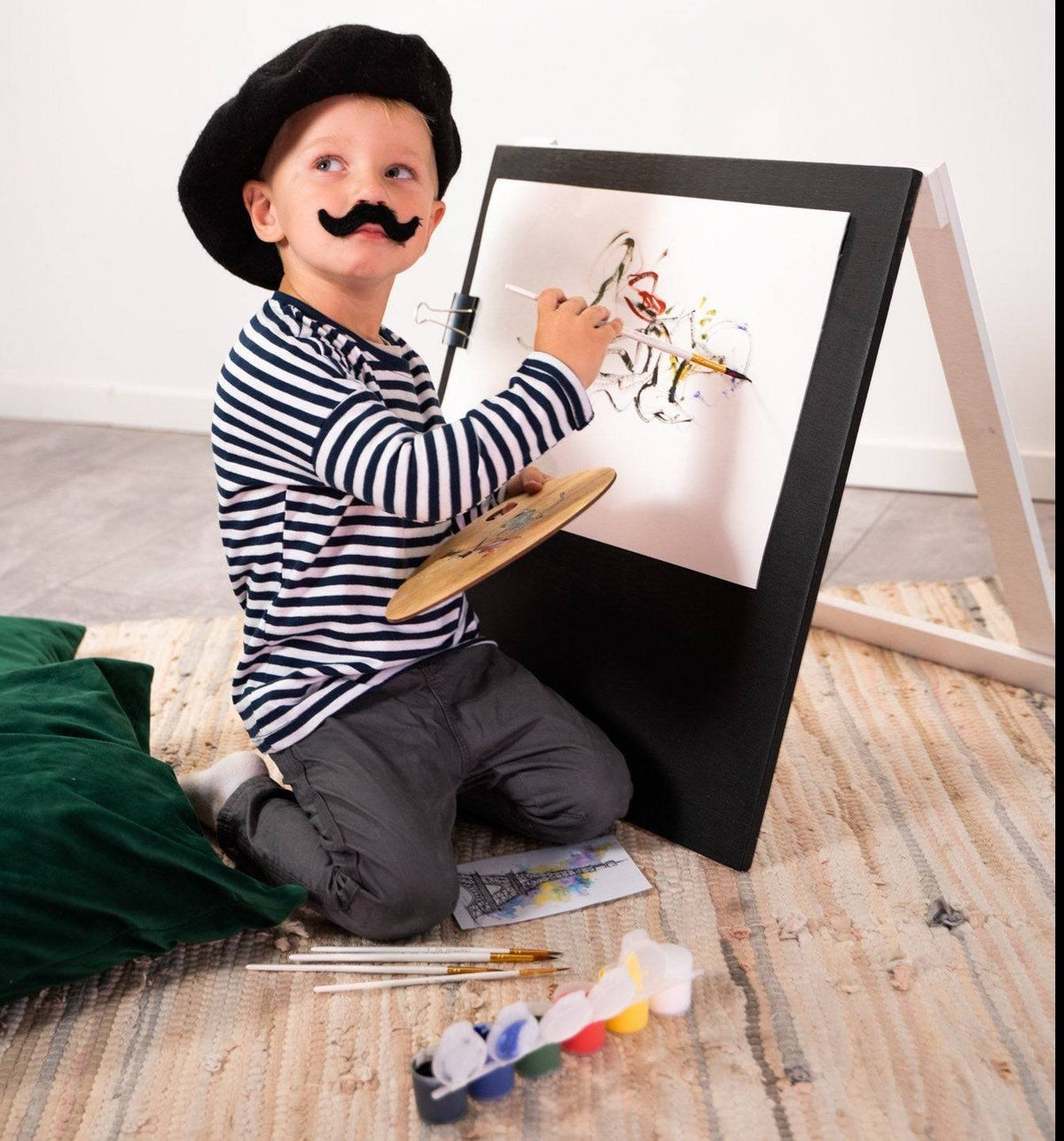 4. Child in striped shirt and beret painting on Ewart Woods black wooden chalkboard easel with paint palette