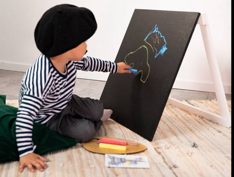 2. Child in striped shirt and beret drawing with chalk on Ewart Woods black wooden chalkboard easel