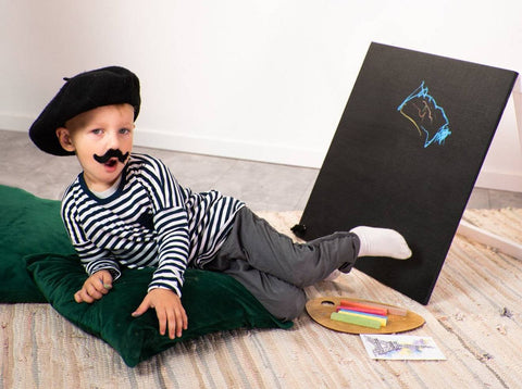 3. Child in striped shirt and beret posing with Ewart Woods black wooden chalkboard easel and art supplies