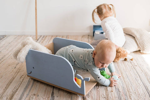 5. Baby playing with toys inside blue whale-shaped wooden toy box on wheels