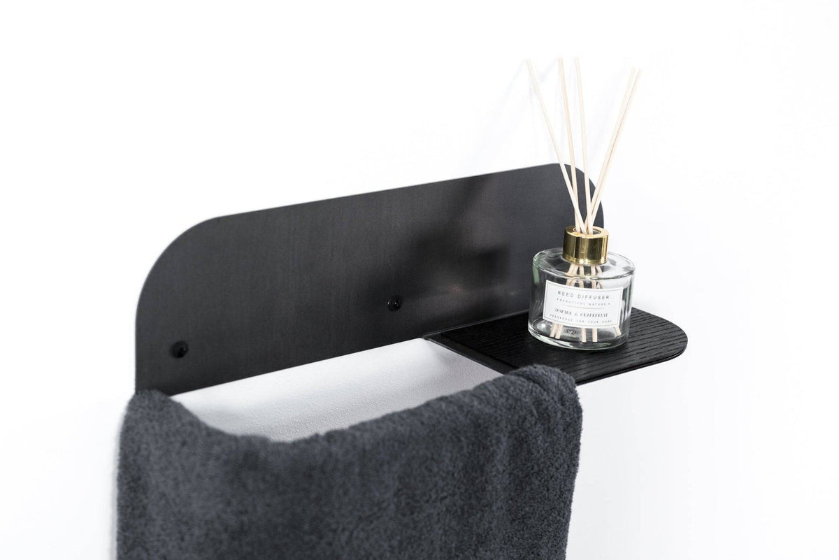 4. Black steel and wood towel rack with dark towel and glass diffuser on shelf, mounted on white wall