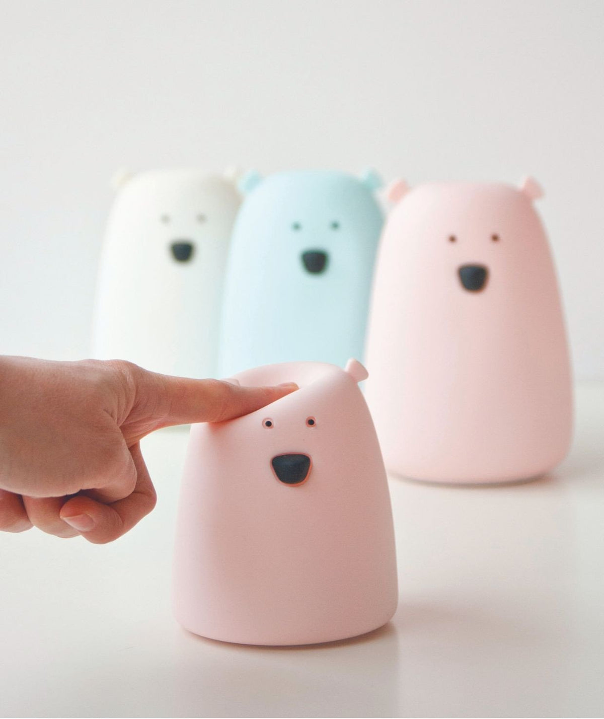 1. Hand tapping a pink Little Bear silicone lamp with other lamps blurred in the background