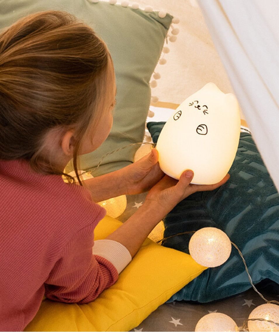 1. Girl holding white Lucky Cat silicone lamp in cozy tent setting with pillows and string lights