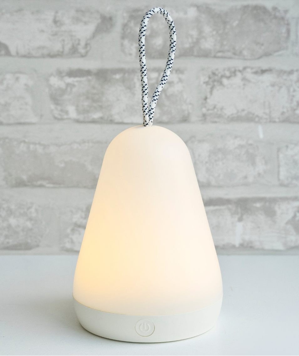 1. White lantern lamp with string handle glowing warmly against a textured brick wall background