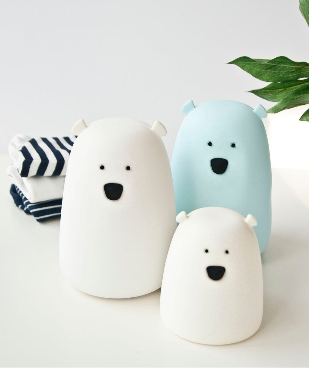 1. Three Little Bear silicone night lamps in white, blue, and white, placed on a table with folded clothes and a plant