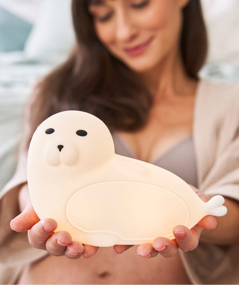1. Woman holding glowing white seal-shaped lamp with a smile