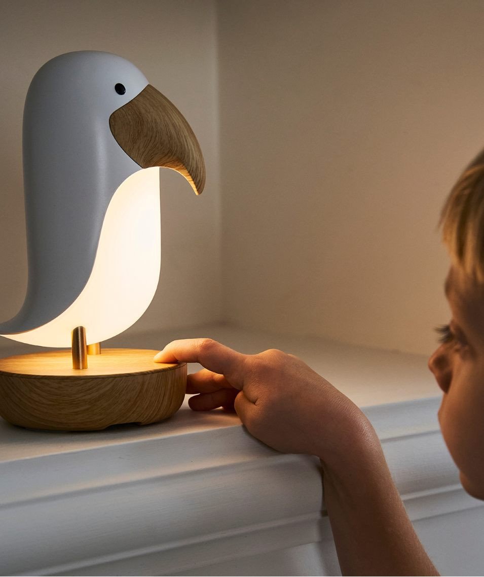 1. Child touching bird-shaped lamp on shelf in dimly lit room