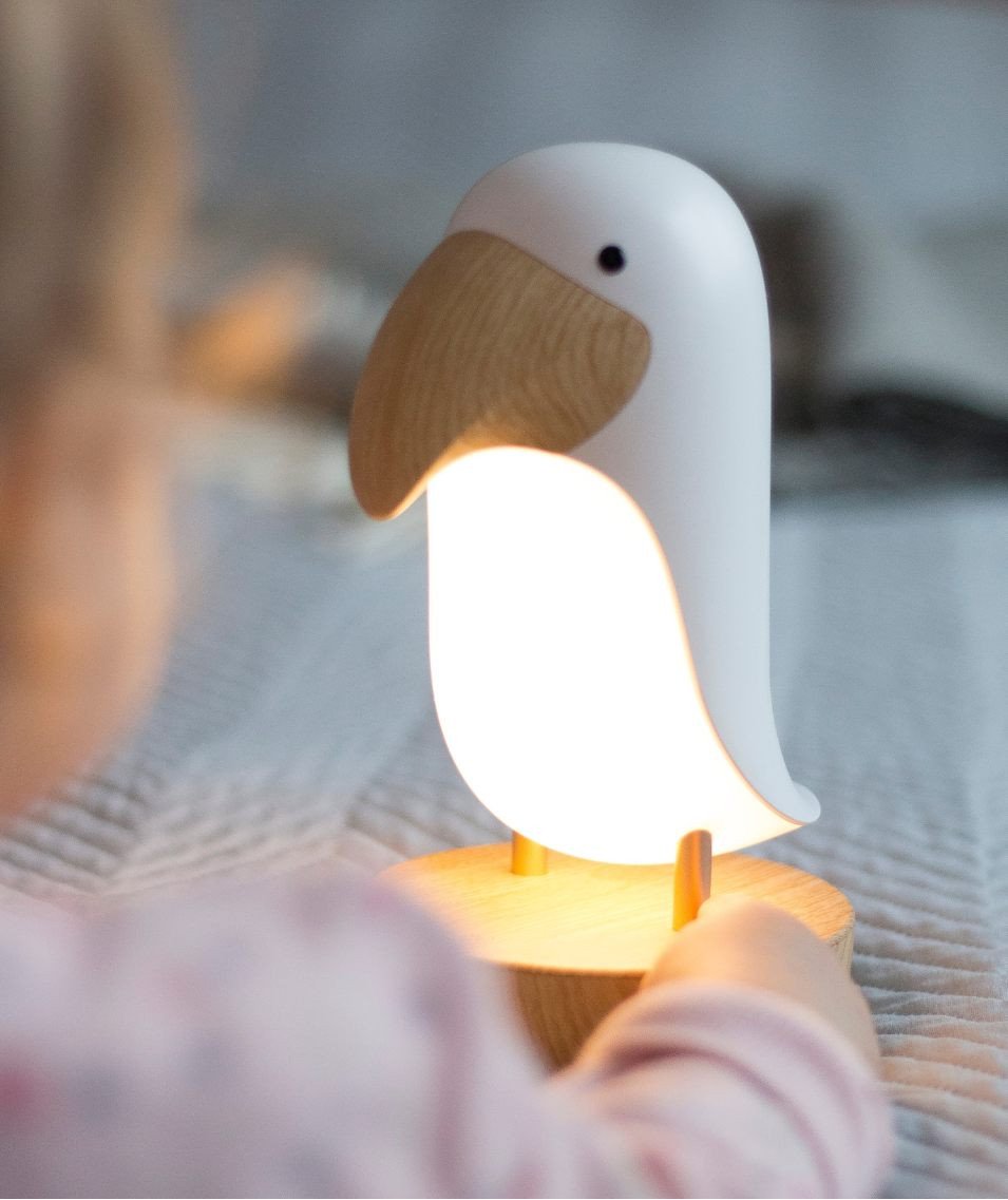 1. Child holding glowing bird-shaped lamp on bed