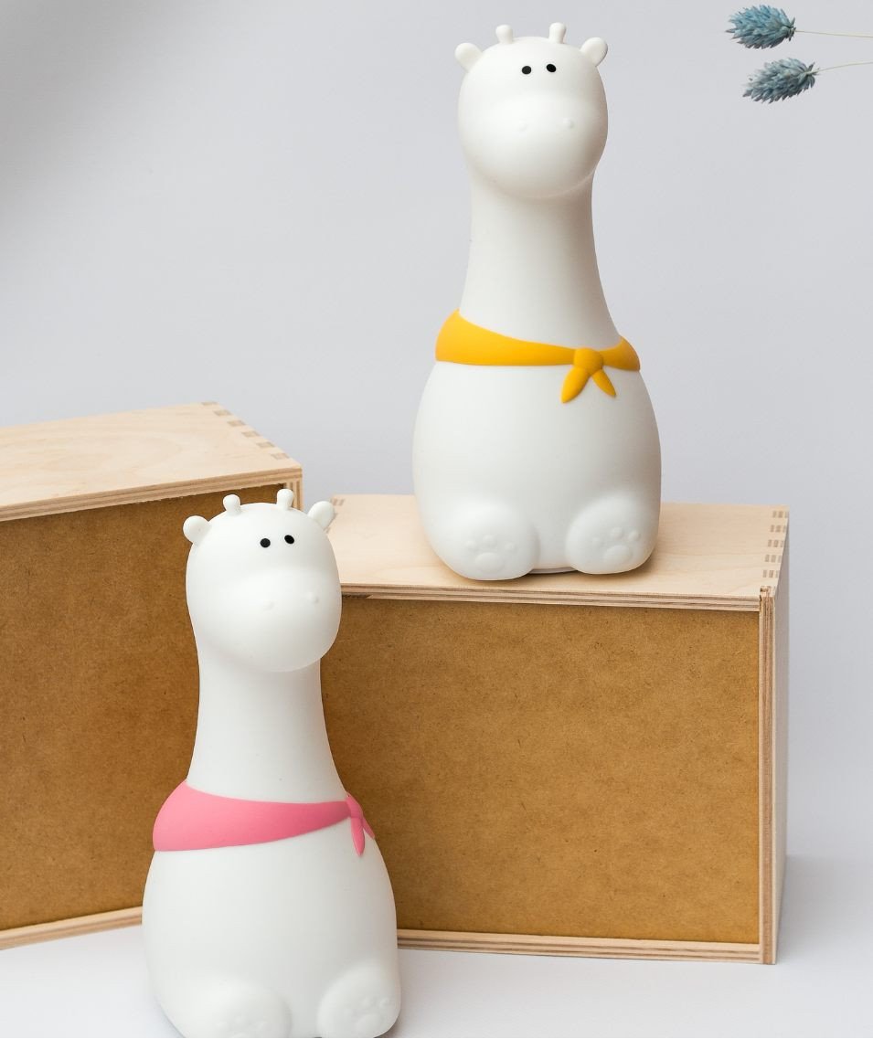 4. Two white silicone giraffe lamps with yellow and pink scarves on wooden boxes