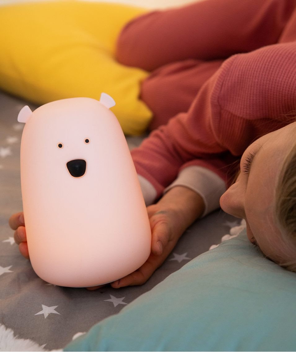 5. Child lying on bed with pink teddy bear-shaped lamp, colorful pillows