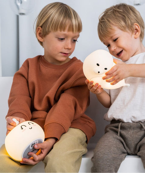1. Two young children playing with white Bunny Silicone Lamp by Rabbit & Friends, sitting on a couch in a cozy setting