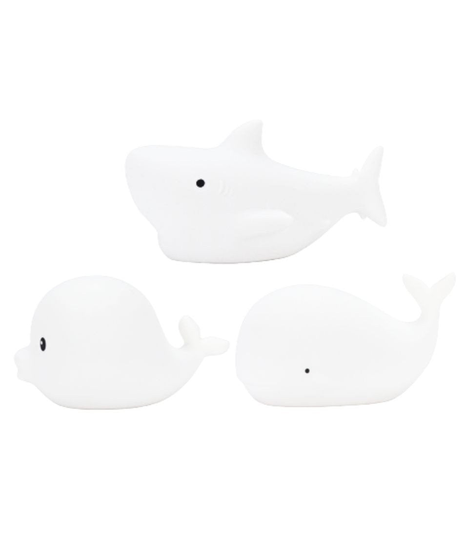 4. Flat lay of three white silicone marine lamps, Dolphin, Whale, and Shark, showing simple design