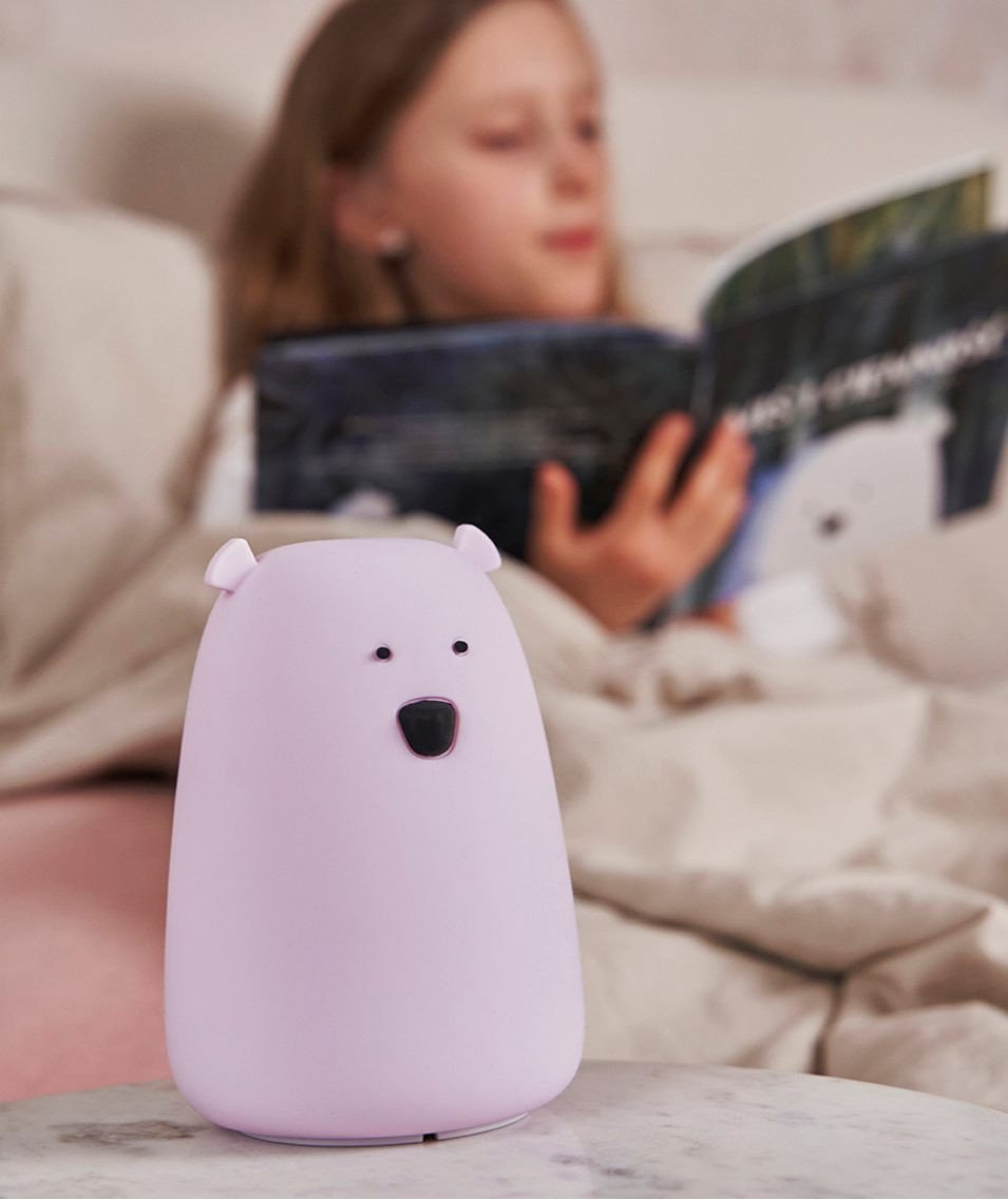 1. Girl reading a book in bed with a lavender Big Bear silicone lamp by Rabbit & Friends on the bedside table