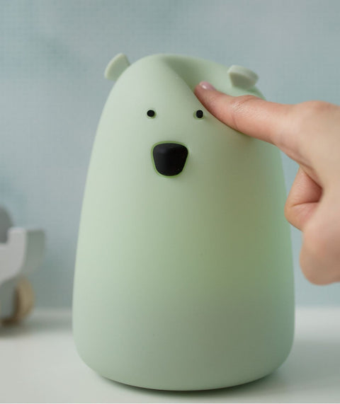 3. Close-up of a hand touching the soft surface of the sage green Big Bear silicone lamp by Rabbit & Friends