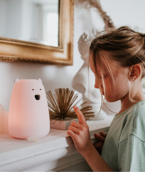 1. Girl interacting with glowing pink bear lamp on mantelpiece