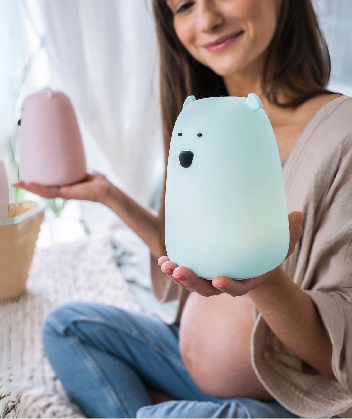 1. Pregnant woman holding blue Big Bear silicone lamp by Rabbit & Friends, sitting on cozy rug