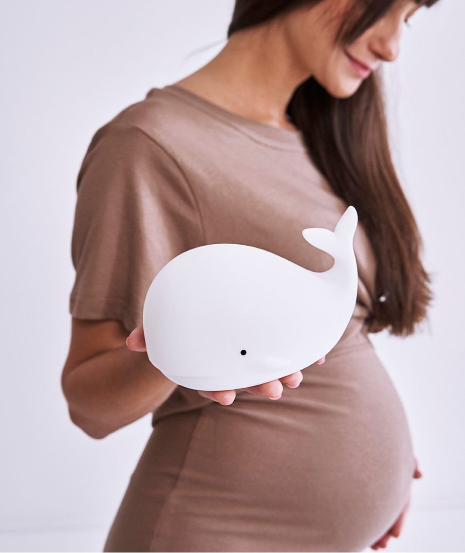 4. Pregnant woman holding white whale silicone lamp in studio setting