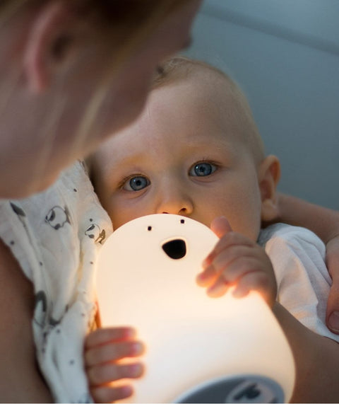 1. Baby holding a glowing white Big Bear silicone lamp while being held by an adult, creating a comforting bedtime atmosphere