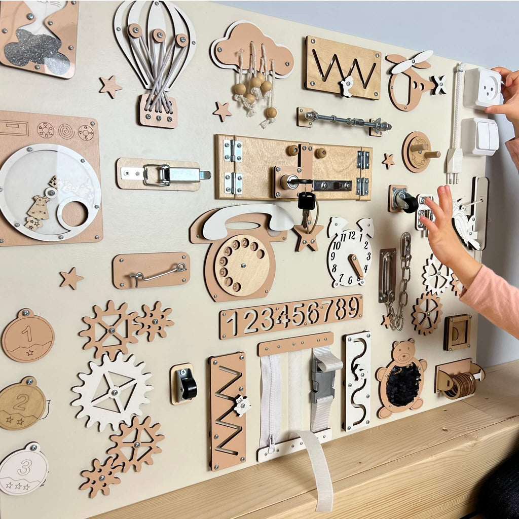 1. Child interacting with BusyBunnyToys extra large Montessori busy board featuring various activities on a wooden surface, ideal for developing coordination and dexterity.