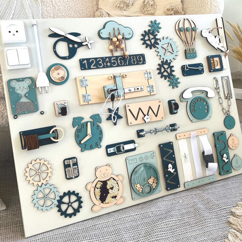 3. Close-up of Montessori busy board with blue and beige elements, highlighting interactive features for sensory play, set against a soft fabric background.