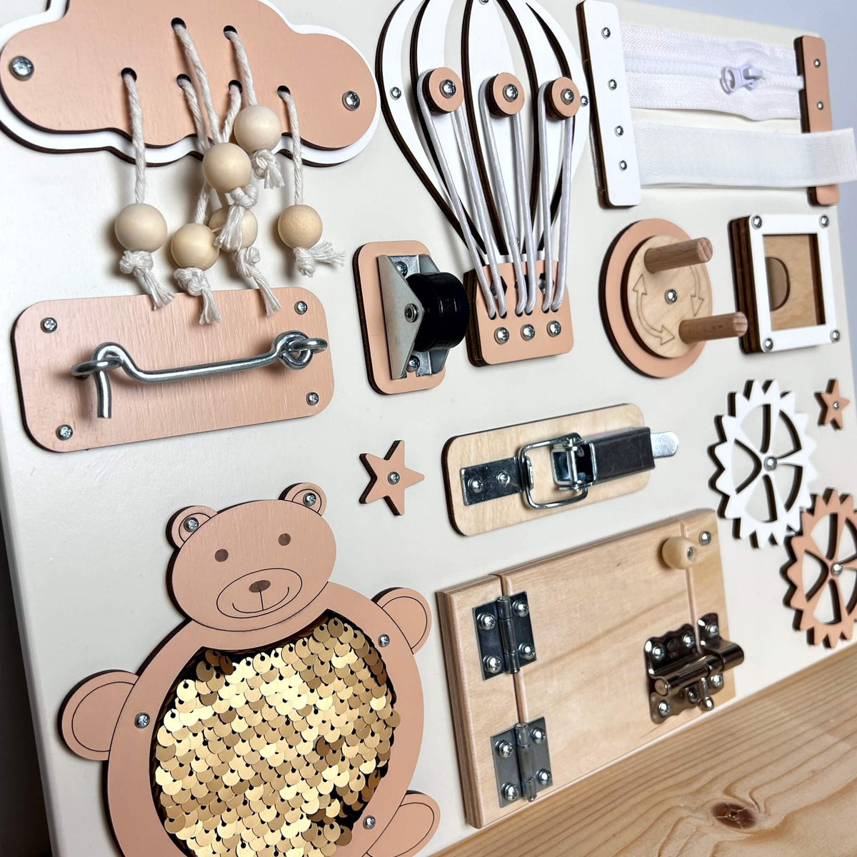 3. Close-up of peach and natural wood busy board with interactive elements like gears and doors