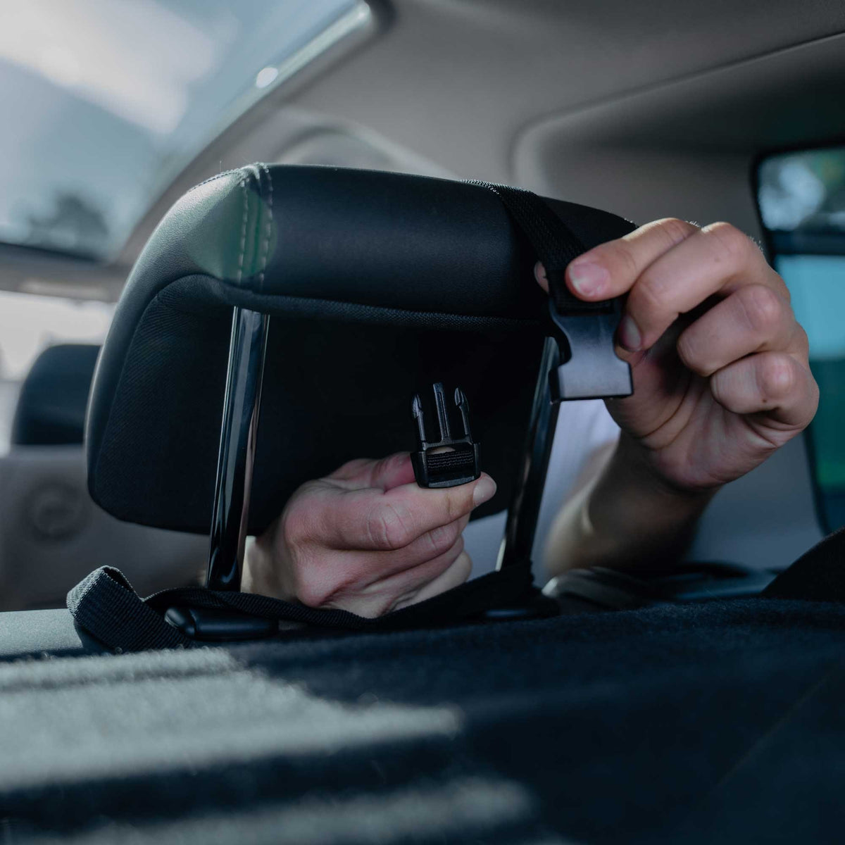 5. Hands installing Ezimoov EZI MIRROR CLASSIC on car headrest with cross straps