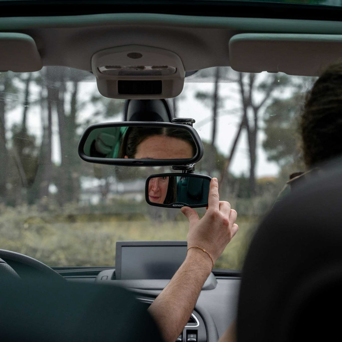 7. Person adjusting Ezimoov EZI Mirror Clip in car, showing rear view