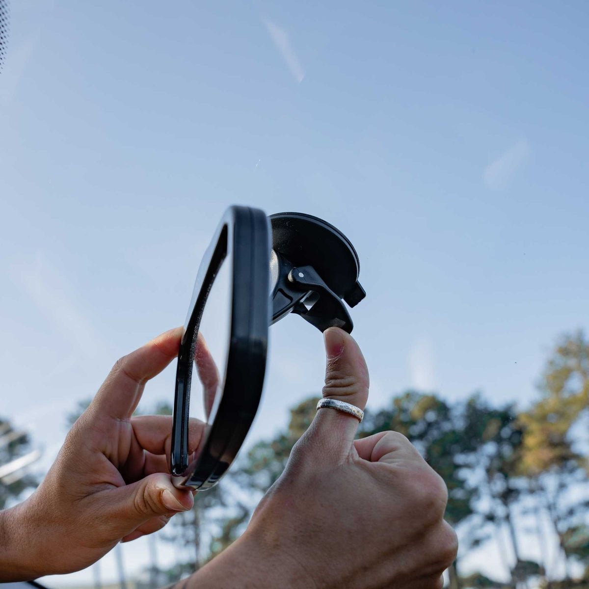 12. Person holding Ezimoov EZI MIRROR MINI with suction cup against blue sky
