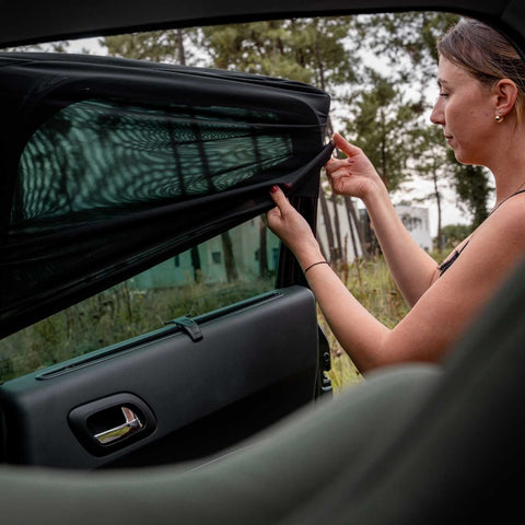 1. Woman installing Ezimoov EZI SUN SOCKS on car window in outdoor setting