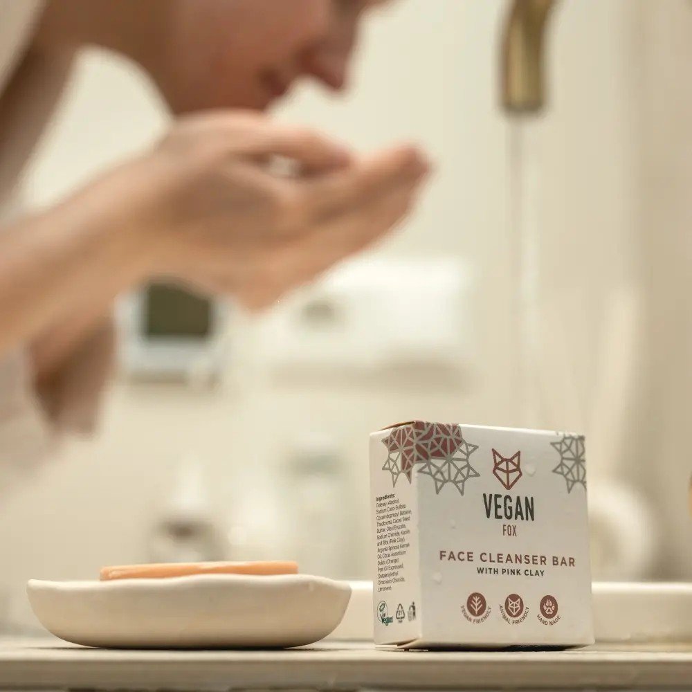 1. Vegan Fox Face Cleanser Bar with Pink Clay in bathroom setting, woman washing face