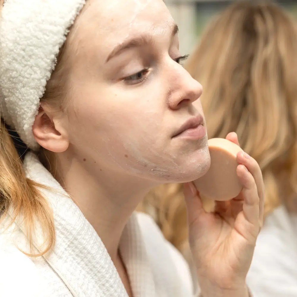 2. Woman applying Vegan Fox Face Cleanser Bar with Pink Clay to face, close-up
