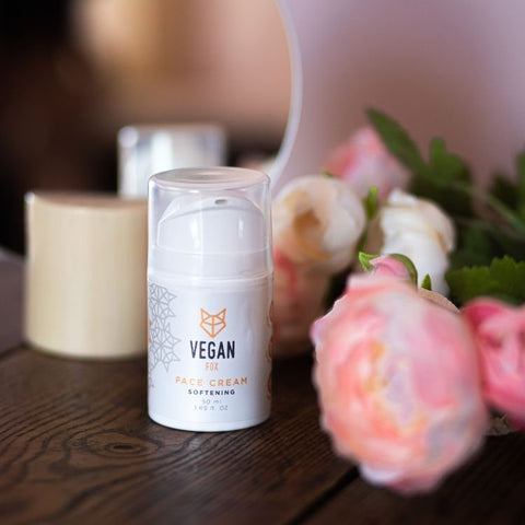 2. Vegan Fox Softening Face Cream on a wooden table with pink flowers, showcasing elegant packaging
