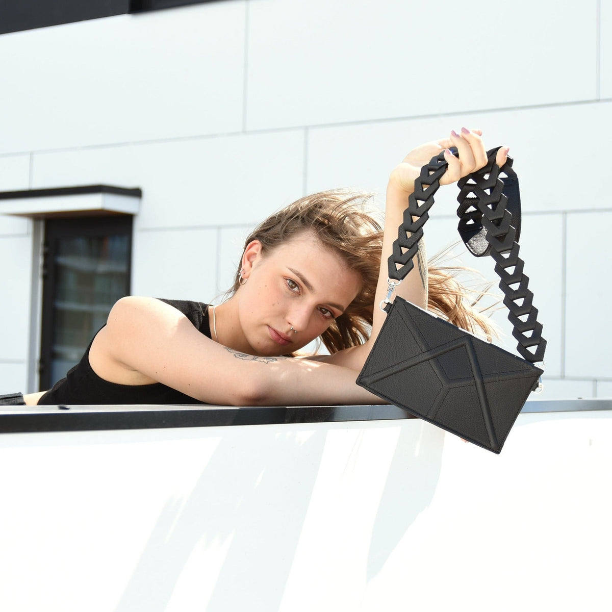 1. Women's black FACET Clutch by Gerda Retter with geometric Venice strap, outdoor lifestyle setting