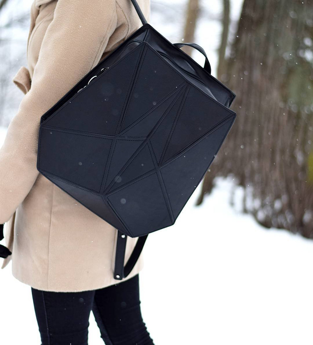 2. Woman wearing Gerda Retter Design FACET black leather backpack in snowy outdoor setting