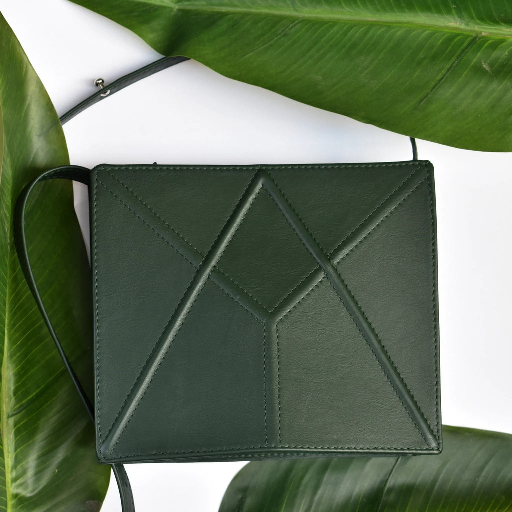 3. Green FACET shoulder bag by Gerda Retter Design displayed on leaves, highlighting geometric design and quality leather