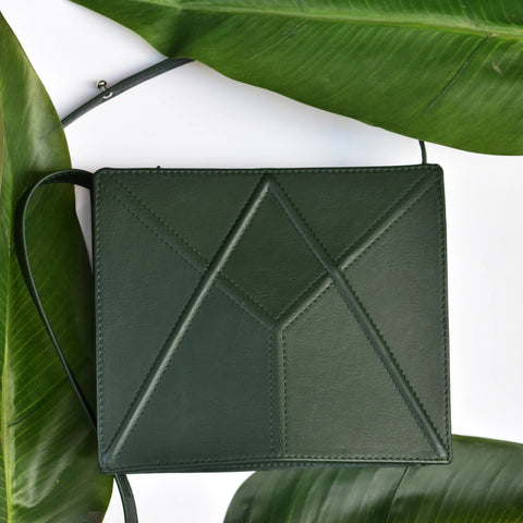 3. Green FACET shoulder bag by Gerda Retter Design displayed on leaves, highlighting geometric design and quality leather