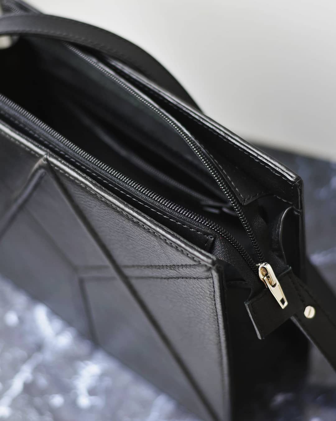 5. Close-up of black FACET shoulder bag by Gerda Retter Design, focusing on zipper and leather texture