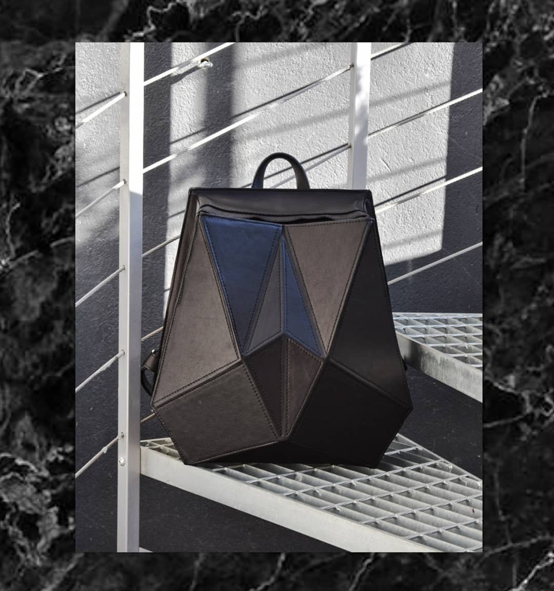 3. Gerda Retter Design FACET black leather backpack displayed on metal stairs, highlighting geometric design