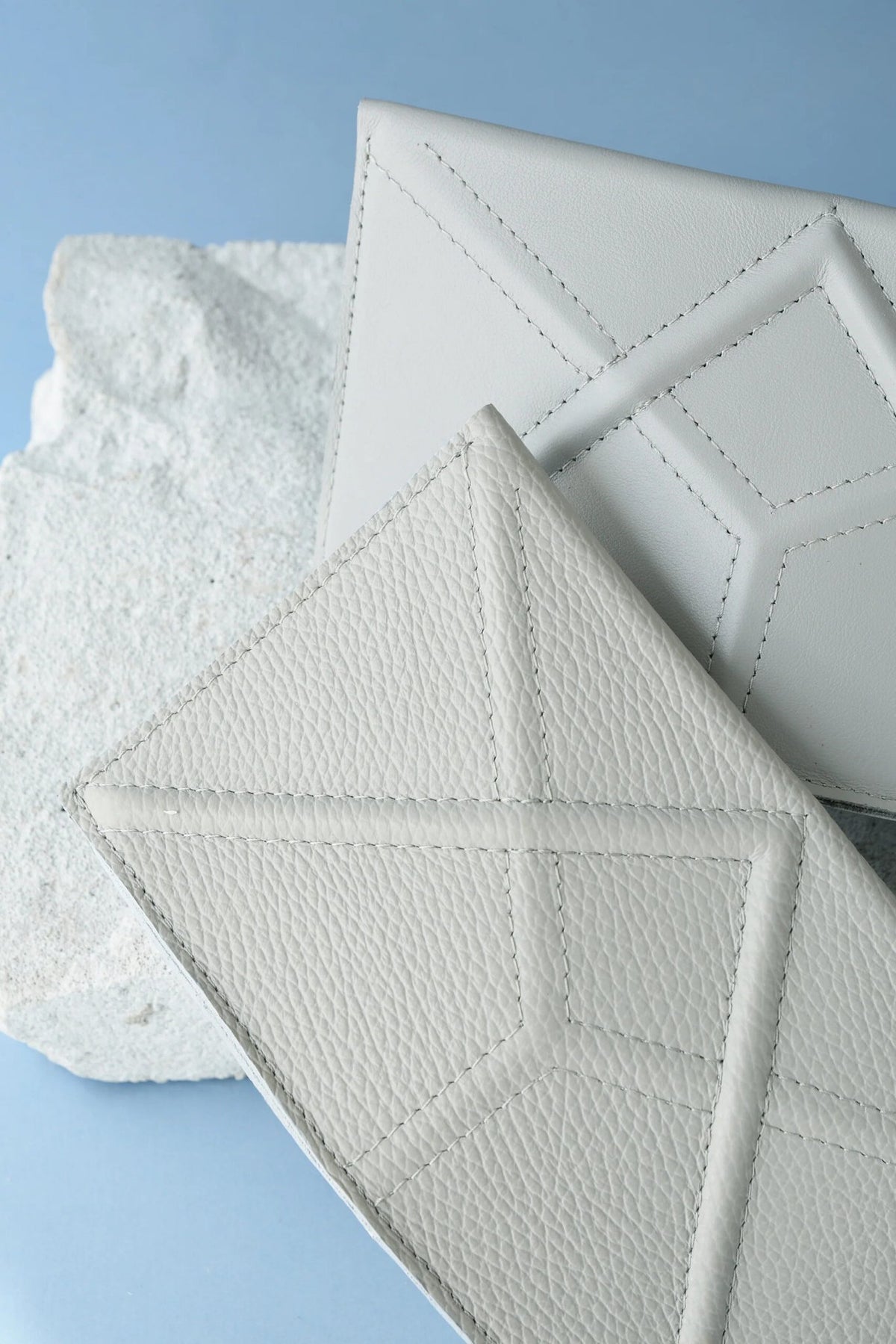 2. Studio shot of two Gerda Retter Design FACET Clutches in light grey, highlighting geometric design on textured leather