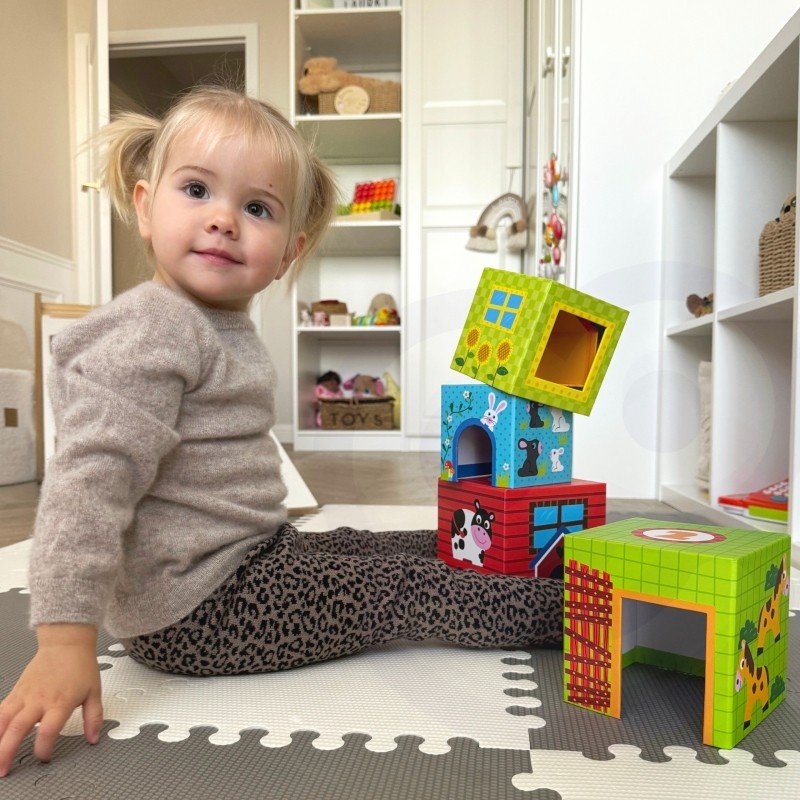 8. Child sitting next to colorful farm-themed cubes on a play mat