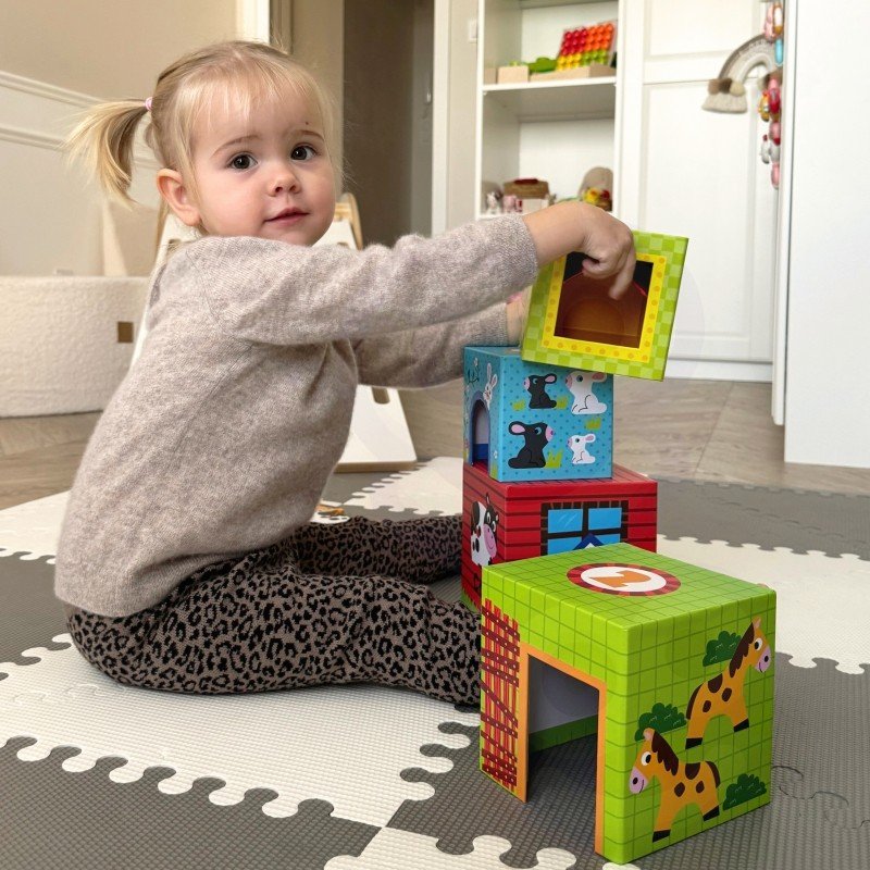 7. Child stacking colorful cubes with animal illustrations on a play mat