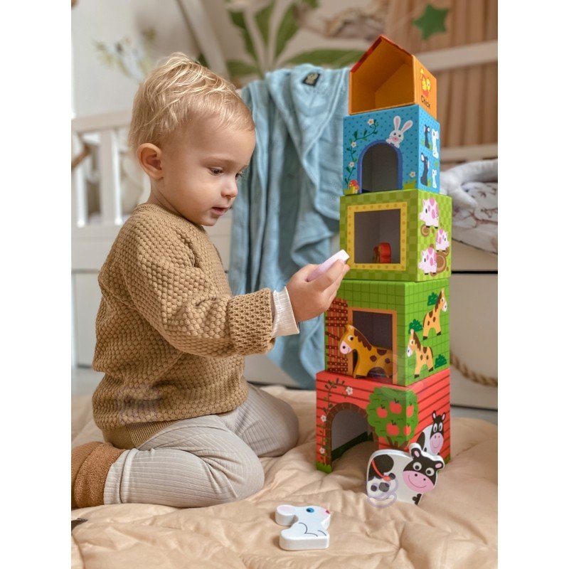 10. Child playing with colorful farm-themed cubes and animal figurines on a beige surface