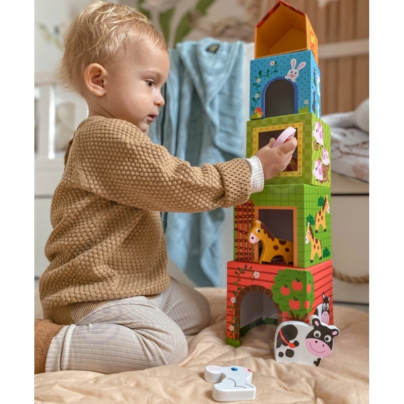 11. Child interacting with colorful farm-themed cubes and animal figurines on a beige surface