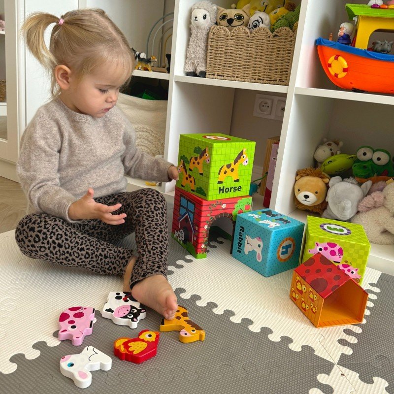 6. Child playing with colorful farm-themed cubes and animal figurines on a play mat