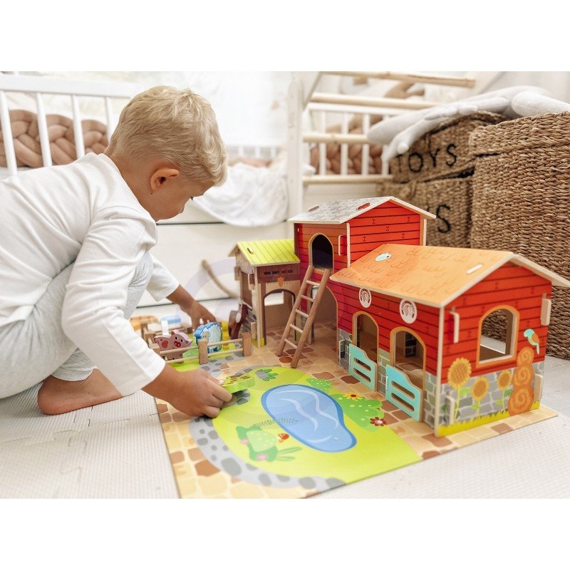 1. Child playing with Woopie Green Mega Farm set on floor, featuring barn, stable, and animal figurines in a nursery