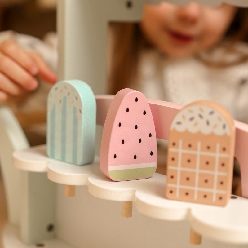 3. Close-up of pastel wooden popsicles on ice cream cart with child playing