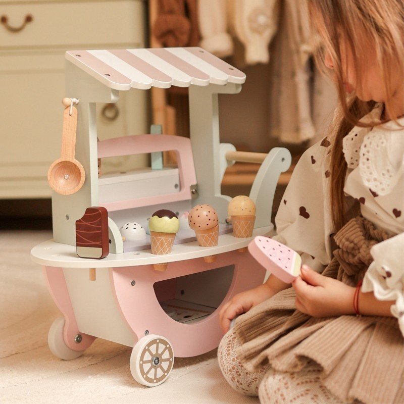 1. Child playing with pastel wooden ice cream cart, holding a popsicle in a playroom