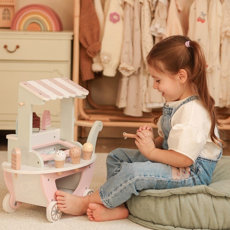 1. Child playing with pastel wooden ice cream cart, sitting on a cushion in a playroom