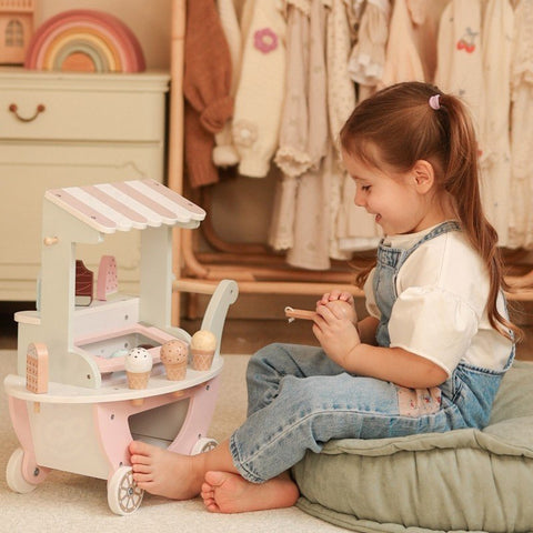 1. Child playing with pastel wooden ice cream cart, sitting on a cushion in a playroom