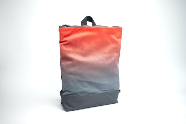 2. Muni salmon faux leather backpack with grey bottom shown at an angle in studio lighting